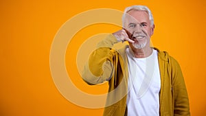 Retired male showing call me gesture, flirting on camera, communication concept