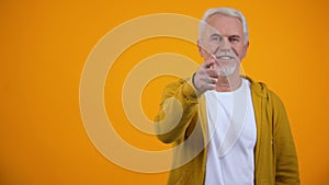 Retired male showing call me gesture, pointing finger on camera, communication