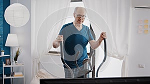 Retired man doing cardio exercise with stationary bicycle