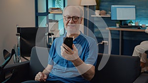 Retired man holding smartphone to chat on video call with family