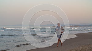 Retired man jogging on the beach at sunset