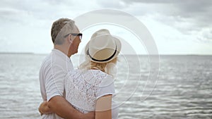 Retired man and mature woman looking to ocean surface together.
