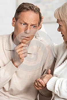 retired man with mental illness holding hand with sad wife.