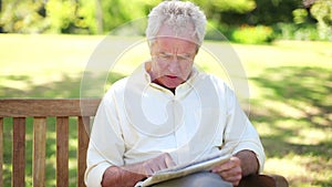 Retired man with a newspaper sitting on a bench