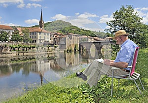 Retired man painting by bank of river