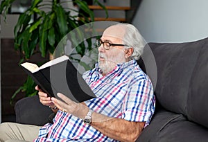 Retired man reading a book in his home