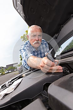 Retired man servicing car engine