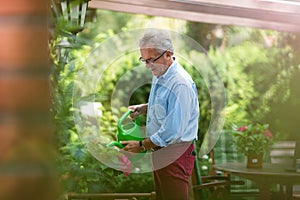 Retired man watering plants in the garden