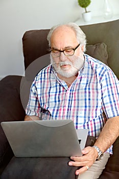 Retired man with white beard sitting in his home