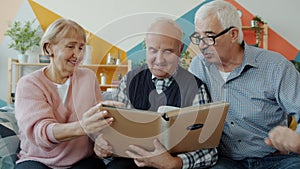 Retired men and woman watching photographs in photobook talking smiling