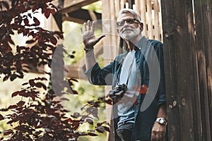 Retired neighbor with a beard greets and smiles on the terrace of the house. Support and care for old people. Thanks to the