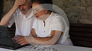 Retired senior couple on a bench with notebook