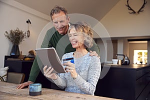Retired Senior Couple At Home Buying Products Or Services Online With Digital Tablet And Credit Card