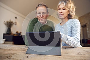 Retired Senior Couple At Home Buying Products Or Services Online Using Digital Tablet