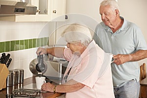 Retired Senior Couple In Kitchen Making Hot Drink Together