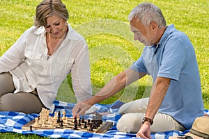 Retired senior couple playing chess in park