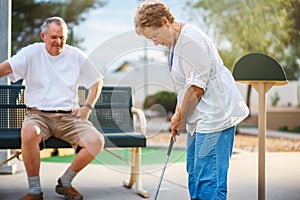 Retired senior couple playing mini golf together