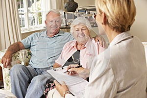 Retired Senior Couple Sitting On Sofa Talking To Financial Advisor