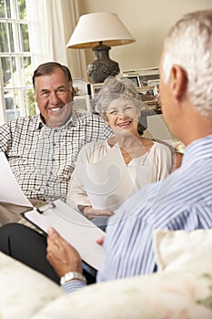 Retired Senior Couple Sitting On Sofa Talking To Financial Advisor