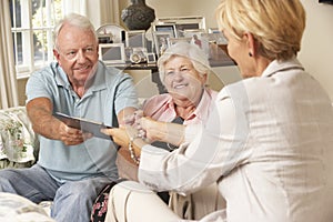 Retired Senior Couple Sitting On Sofa Talking To Financial Advisor