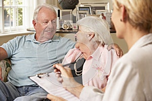 Retired Senior Couple Sitting On Sofa Talking To Financial Advisor