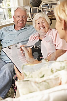 Retired Senior Couple Sitting On Sofa Talking To Financial Advisor