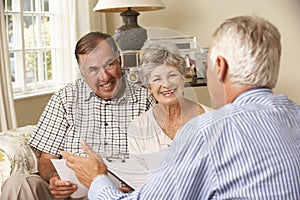 Retired Senior Couple Sitting On Sofa Talking To Financial Advisor