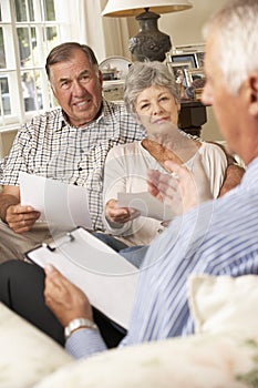 Retired Senior Couple Sitting On Sofa Talking To Financial Advisor