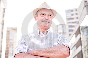 Retired senior hispanic man with hat standing and smiling
