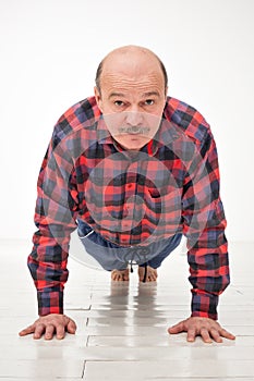 Retired senior man on abdominals workout doing basic plank