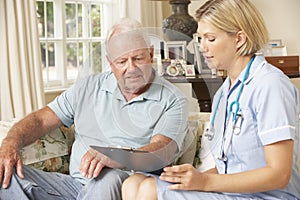 Retired Senior Man Having Health Check With Nurse At Home