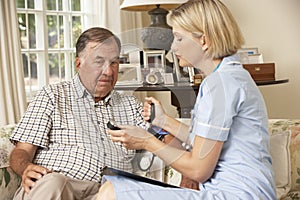 Retired Senior Man Having Health Check With Nurse At Home