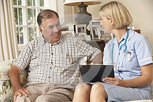 Retired Senior Man Having Health Check With Nurse At Home