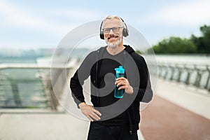 Retired sportsman have outdoor workout, holding bottle of water