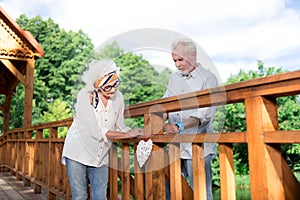 Retired wife and husband hanging handmade heart on the wooden bridge