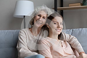 Retired woman grandma sit on sofa hug adult granddaughter