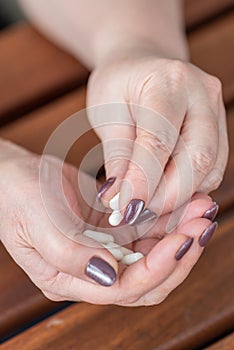 A retired woman holds a handful of capsules in her hands.