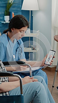 Retired woman and nurse talking to doctor on video call