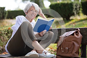 Retired woman reading book on bench