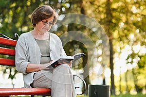 Retired woman reading a book on the bench
