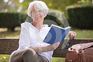 retired woman reading book on bench