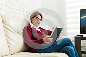 Retired Woman Reading Book At Home
