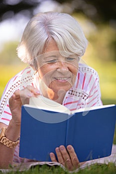 Retired woman reading book on park