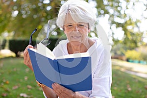 retired woman reading book at park