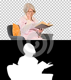 Retired woman reading a book sitting on a chair, Alpha Channel w