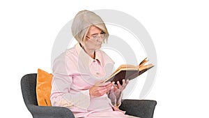 Retired woman reading a book sitting on a chair on white background.