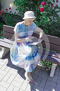 Retired woman reading newspaper outdoors