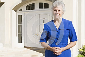 Retired woman standing outside house