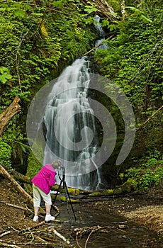 Retired woman taking pictures of a waterfall