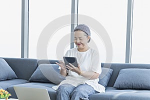 A retired woman using a tablet and laptop in the living room in the morning